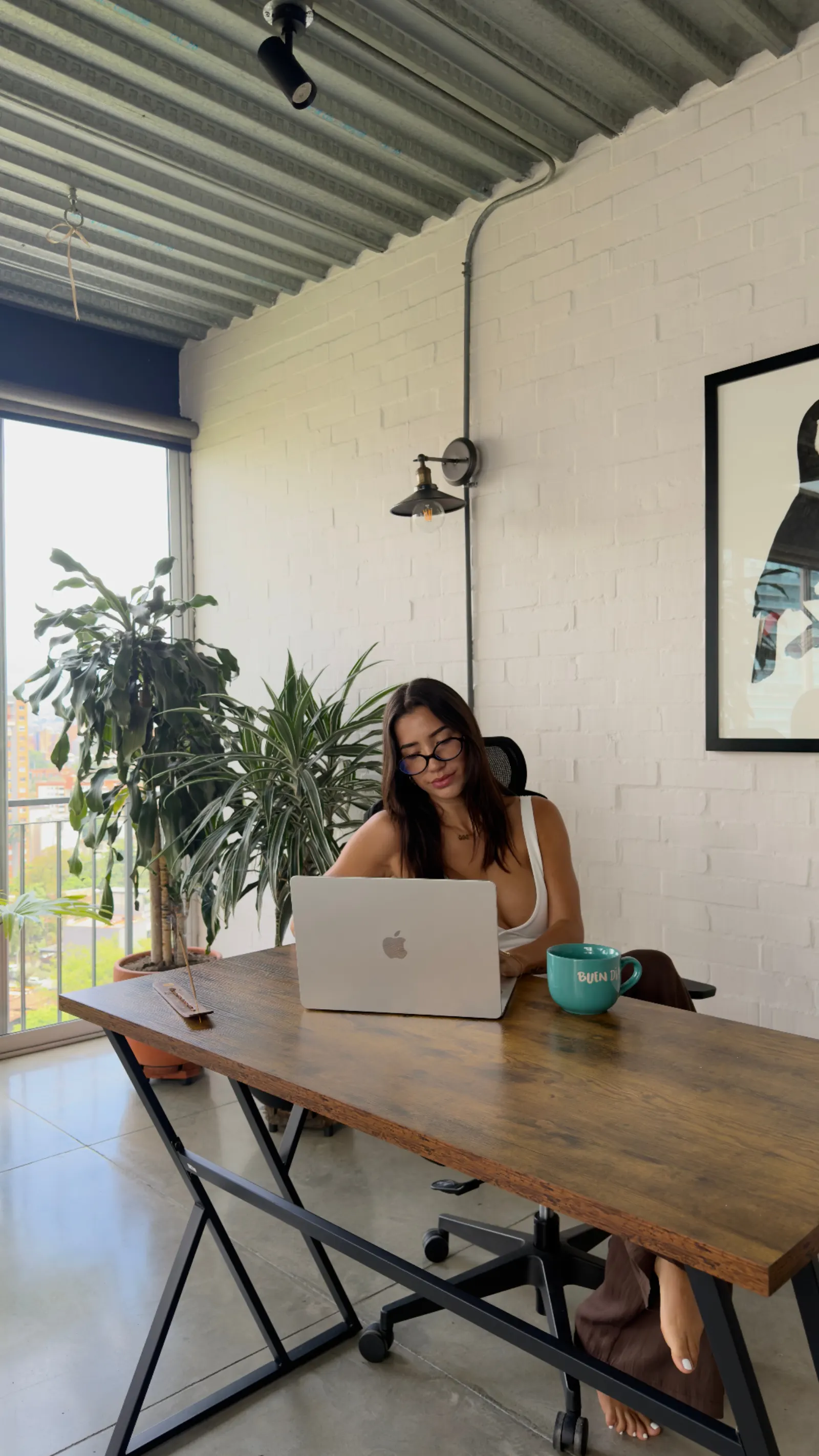 Working focused at a sunlit desk with laptop and coffee